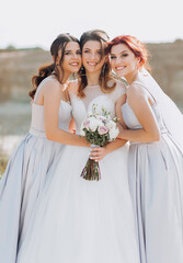 Incredible bride with her girlfriens posing against the backdrop of sand rocks.