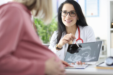 Female doctor demonstrates fetal ultrasound scan to pregnant woman.