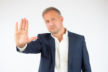 Handsome young business man white wall with open hand doing stop sign with serious and confident expression, defense gesture.