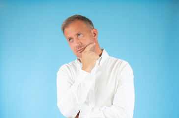 Young man in casual shirt thinking over blue background.