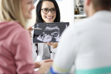 Doctor demonstrates child's ultrasound to couple closeup