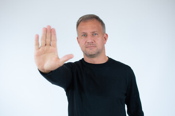 Naklejka premium Handsome young man white wall with open hand doing stop sign with serious and confident expression, defense gesture.