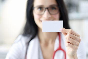 Smiling doctor portrait holding white business card in hand