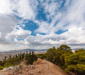 Fototapeta na wymiar View of Athens from Strefi Hill during a morning with beautiful white clouds. The hill is located in Exarchia district, in downtown Athens, Greece, Europe