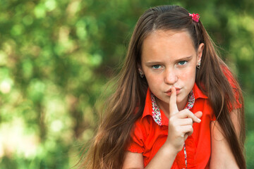Hushing, young girl with her finger over her mouth.
