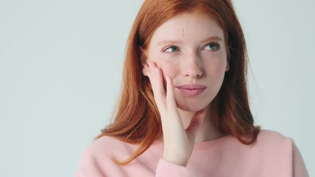 Cute thinking redhead girl posing isolated over white wall background