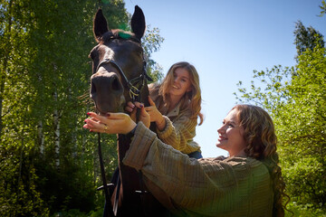 Two girls with big horse in a summer day