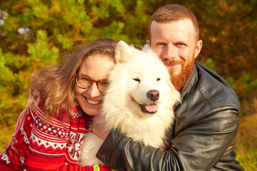 Cute girl and man with dog in the autumn sunny day. Friendship of man, woman and dog. Couple walking with pet.