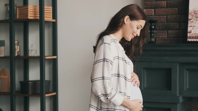 Young pregnant optimistic woman walking indoors at home