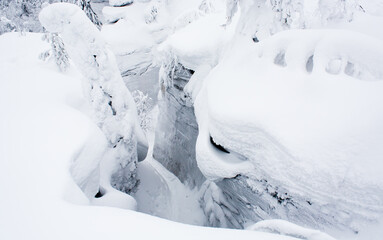 Fototapeta na wymiar A secret path between large stones under huge snowdrifts in a winter forest