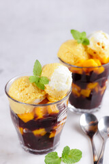 Indonesian traditional dessert: Bubur Ketan Hitam or black glutinous rice porridge with mango slice topping with coconut and mango ice cream.