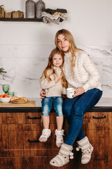 happy mother and little daughter hugging while having breakfast at home in morning
