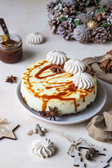 Vanilla cheesecake with carrot cake crust served with salty caramel topping and meringue, light concrete background.