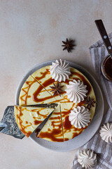Vanilla cheesecake with carrot cake crust served with salty caramel topping and meringue, light concrete background.