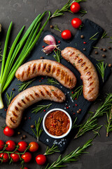 Grilled sausages with rosemary herbs and tomatoes on a black background. Top view - 396757865