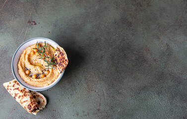Classic hummus with rosemary, flatbread, boiled chickpea and olive oil, green stone background. Traditional Middle Eastern snack. Top view.