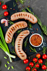 Grilled sausages with rosemary herbs and tomatoes on a black background. Top view - 396758094