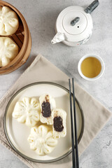 Bakpao or pao or chinese steamed bun in traditional bamboo steamer serve with tea in top view.