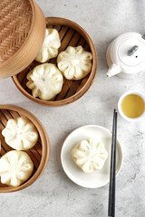 Bakpao or pao or chinese steamed bun in traditional bamboo steamer serve with tea in top view.