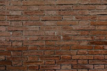 Obraz premium Rustic brick wall with colorful red brown bricks uneven and cracked with space for texture background