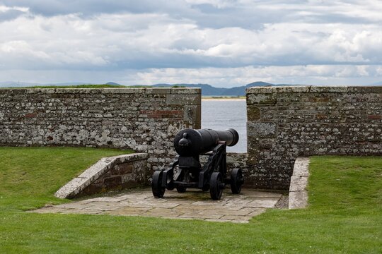 Stone brick protective wall and war cannon at barracks complex in historical Fort George, Scotland