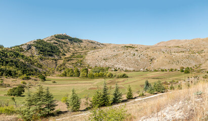 Naklejka premium green upland below medieval castle ruins, Rocca Calascio , Abruzzo, Italy