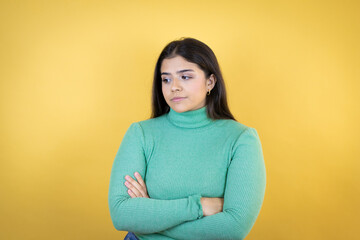 Young caucasian woman over isolated yellow background thinking looking tired and bored with crossed arms