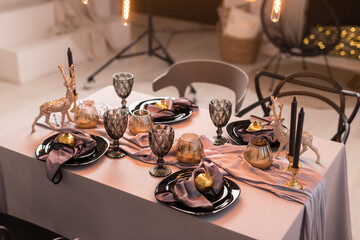Fototapeta na wymiar Top view of festive Christmas table setting with empty wine glasses and black plate with gray napkins