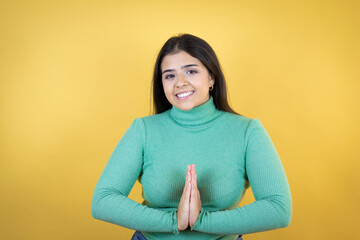 Fototapeta premium Young caucasian woman over isolated yellow background begging and praying with hands together with hope expression on face very emotional and worried