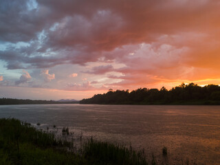 Landscape with river, colorful clouds, water grass and mountain in distance at sunset. Dramatic...