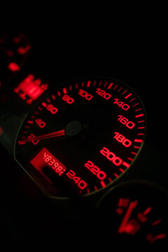 Speedometer with red light at night close-up. Car dashboard. Vertical photo