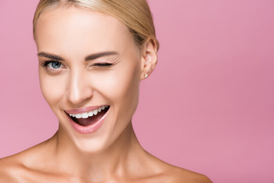 beautiful blonde woman with perfect skin winking isolated on pink