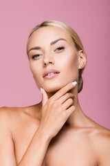 beautiful blonde woman with perfect skin touching face isolated on pink