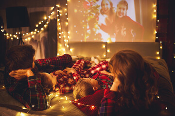 family mother father and children watching projector, TV, movies with popcorn in   christmas...