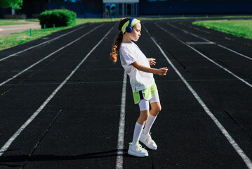 Fototapeta na wymiar Girl jogging on a sunny summer evening, laying on treadmill, stadium, physical training, back to school.