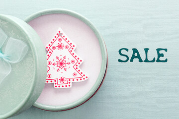 New year's card in honor of holiday sales. Open gift box with decorative Christmas tree inside. The inscription sale.