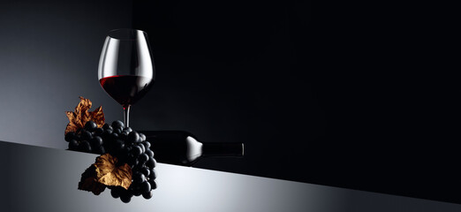 Red wine and blue grapes with dried up vine leaves on a dark background. © Igor Normann