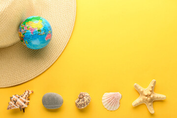 Tourist theme: hat, globe, seashells, starfish, and rock on a yellow background. Travel accessories. The globe shows Eurasia, China, India.