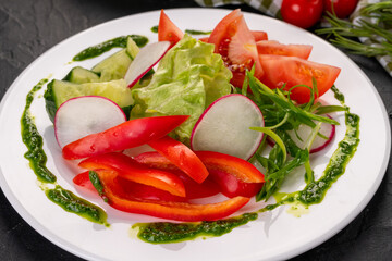 fresh sliced vegetables (peppers, cucumbers, tomatoes, lettuce and radishes) on a white plate for the restaurant menu.