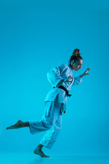 Active training. Professional female judoist in white judo kimono practicing and training isolated...