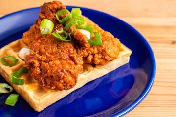 Homemade Southern American comfort street food fresh deep fried crispy stacked chicken wings with buffalo red chili spicy hot sauce and waffle sweet maple syrup