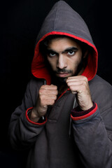 young man in hoodie  showing fist in anger in black ground