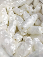 Lots of white polyester and silk threads. Sewing machine spools. Background on the theme of light...