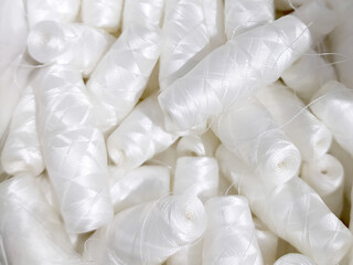 Lots of white polyester and silk threads. Sewing machine spools. Background on the theme of light...