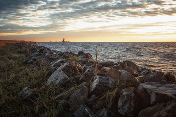 The dike around the island of Marken during sunrise with the lighthouse Het Paard van Marken in the...