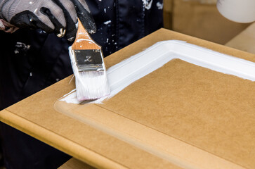 Repainting kitchen cabinet doors with white chalk paint indoors at home. Giving old kitchen new...