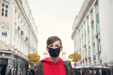 Young man in a black protective mask against background of the city