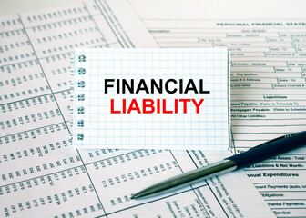 Notepad with text Financial Liability lying on financial tables with a pen