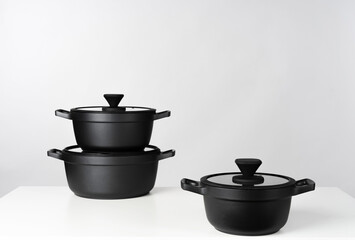 Black cooking pots on grey background front view