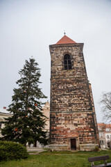 Fototapeta na wymiar Gothic medieval stone bell tower near baroque saint Gothard church in old historic center of Cesky Brod, Christmas tree and Christmas decorations, Central Bohemia, Czech Republic